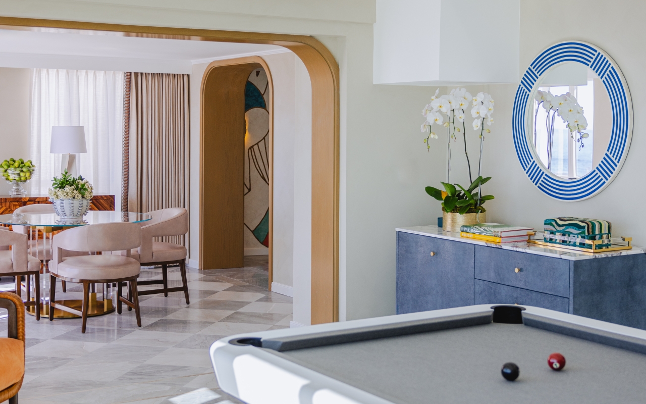 Luxury Regent Santa Monica resort Presidential Suite with a grand living area, curved sectional, marble dining table, and floor-to-ceiling ocean views opening to a private furnished balcony.