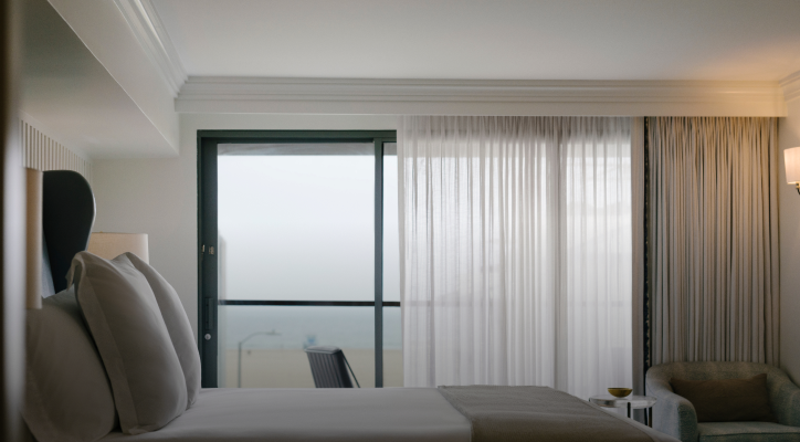 view of ocean through drawn curtains in the Sunset Penthouse Suite