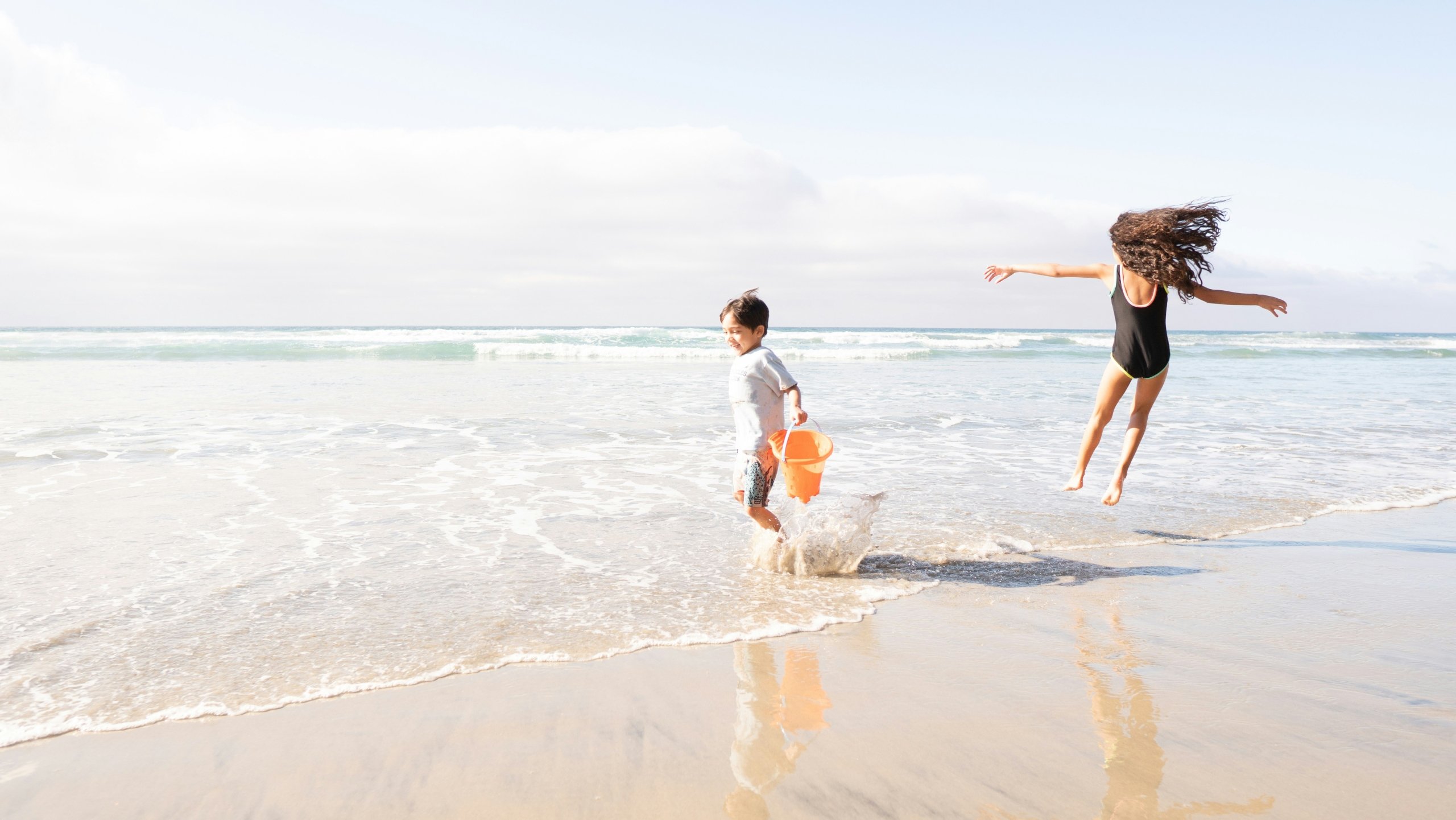 A young boy and girl play in the waves on Santa Monica beach, in front of Regent Santa Monica Beach Hotel.