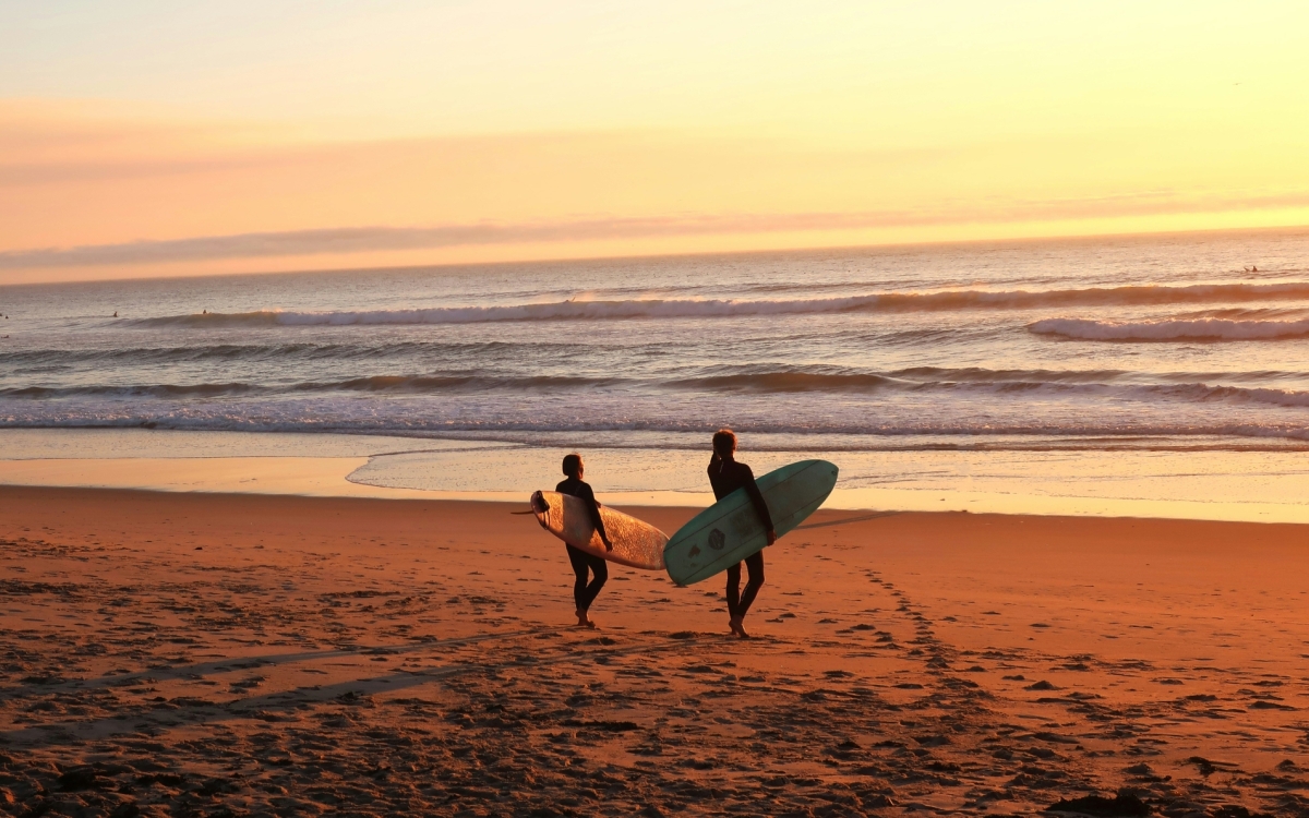 two surfers with surfboards at sunrise