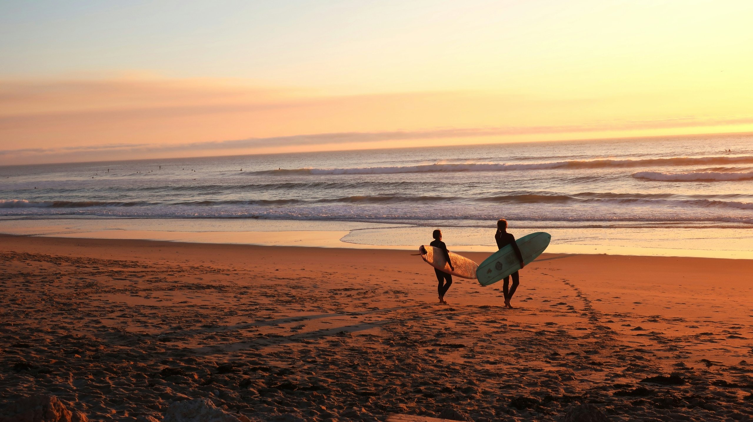 two surfers with surfboards at sunrise