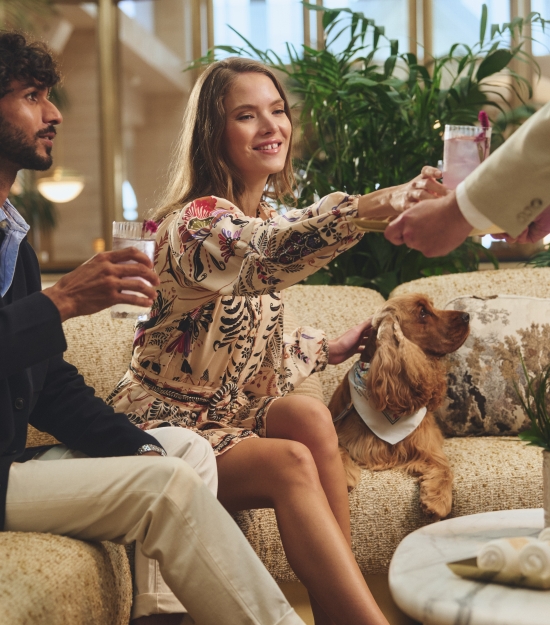 Couple with dog sitting at lobby being served drinks