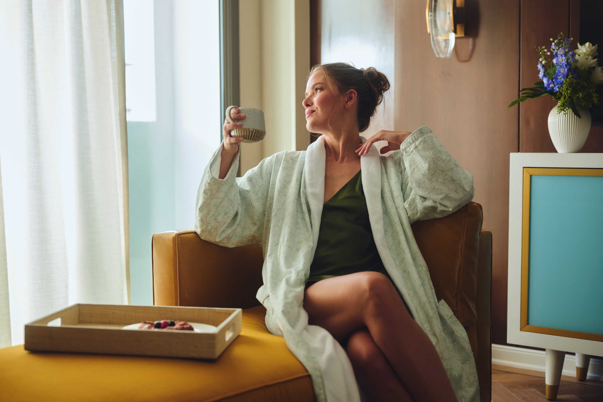 Woman with coffee in hand in hotel room