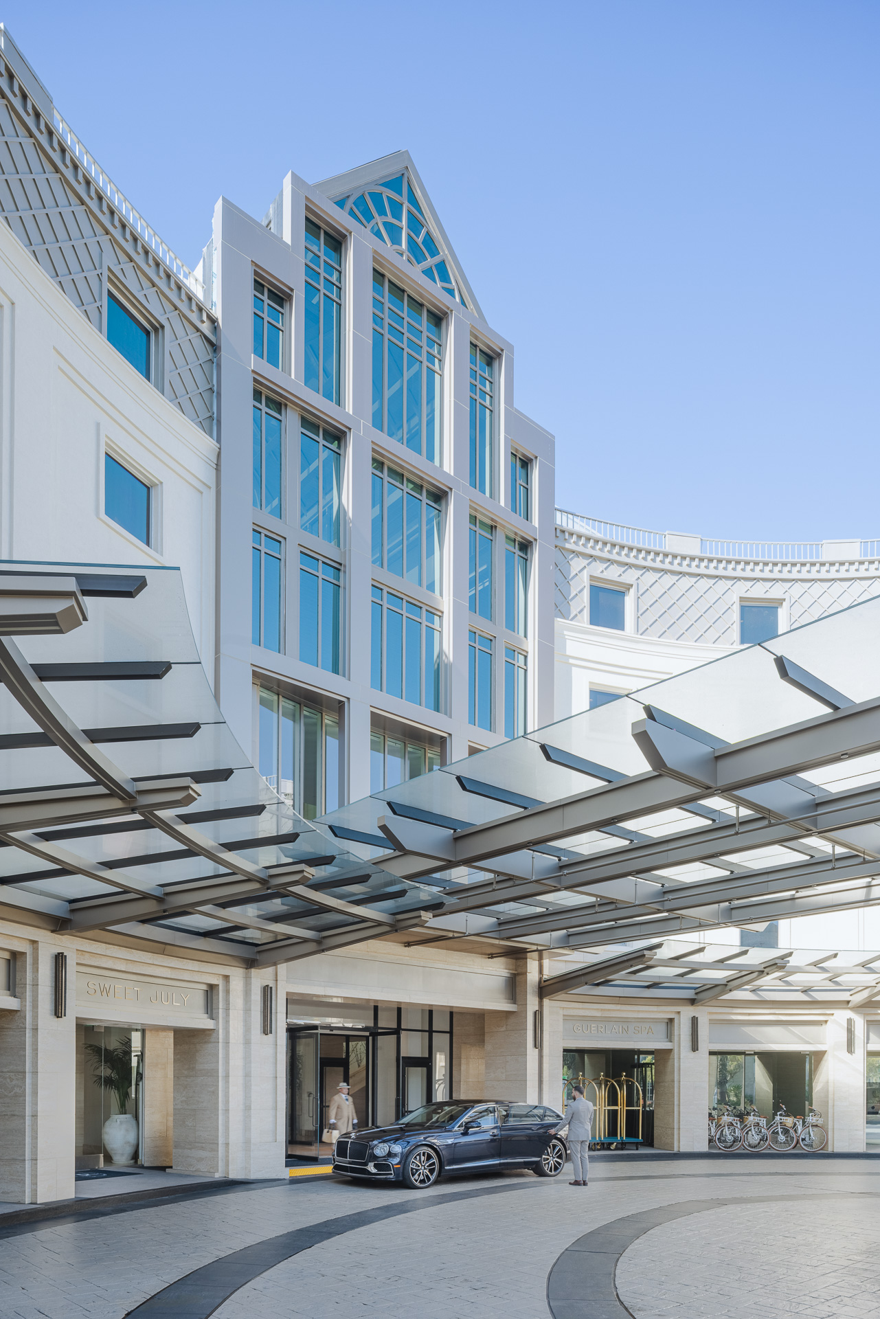 Front of luxury hotel with car and bellhop in driveway