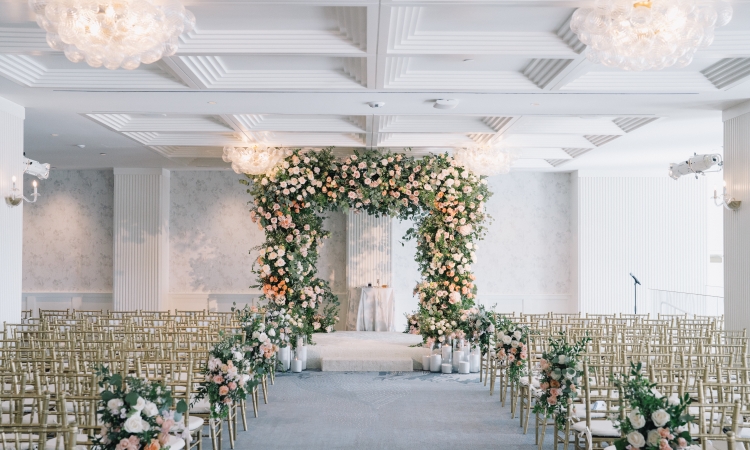 A breathtaking wedding arch stands at the heart of the Regent Santa Monica’s luxury venue, adorned with a lush arrangement of orange, white, and yellow blooms.