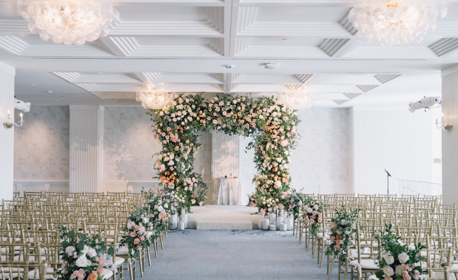 A breathtaking wedding arch stands at the heart of the Regent Santa Monica’s luxury venue, adorned with a lush arrangement of orange, white, and yellow blooms.