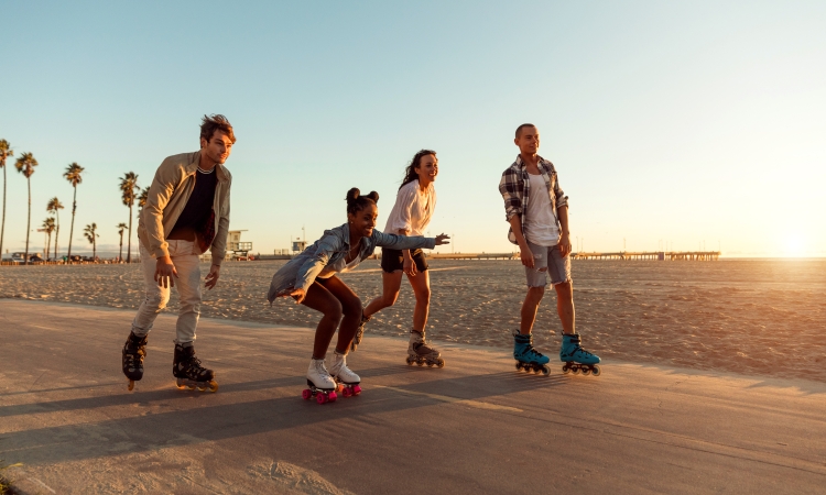 Friends roller skating on the boardwalk in Venice Beach - Santa Monica promenade - Los Angeles, USA